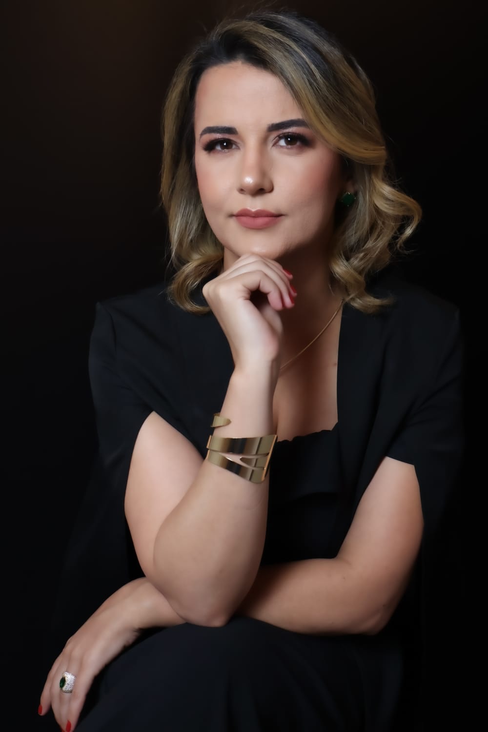 Luana Ribeiro, advogada, em retrato de estúdio com blazer preto sobre fundo escuro.